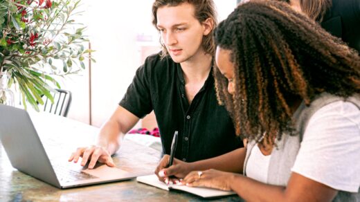 Three diverse colleagues collaborating around a laptop and notebook in a bright modern workspace